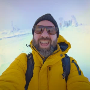 Das Team Serwo Schamutzki mit gelber Winterjacke macht Selfie auf verschneitem Berg.